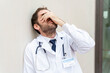 © StockMe - Doctor feeling distressed and overwhelmed by work, leaning against a wall, facing challenges in the healthcare system