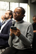 © DC Studio - Black female journalist reading questions out loud from her phone, interacting with presenter and engaging in business discussion. Young woman writing down answers for press purposes.