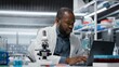 © DC Studio - Molecular biologist in lab analyzing batch of blood samples for red blood cell abnormalities. African american man doing research on sanguine fluid vials to diagnose anemia types, camera B