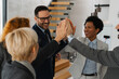 © Novak - A diverse team of successful business professionals celebrating a victory in a modern office. They are cheering, raising their hands, and making triumphant gestures after closing a deal