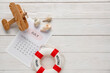 © Pixel-Shot - Calendar with lifebuoy, seashells and toy plane on white wooden background. Summer vacation concept