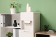 © Pixel-Shot - Modern water cooler and shelving unit near green wall in stylish office
