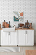 © Pixel-Shot - Table with sink and utensils near white brick wall in kitchen
