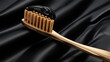 © kainat - A close up of a gold toothbrush with black toothpaste on a black satin background in a studio setting
