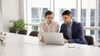 © fizkes - Two focused European company staff members working together on presentation using laptop, editing business document, researching market trends, planning next step for project, evaluating sales results