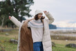 © SHOTPRIME STUDIO - Woman wearing a long beige puffer coat and knit sweater outdoors, enjoying a windy day by the shore, casual winter fashion and cozy cold weather style for a relaxed lifestyle shoot
