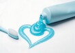 © Helen - Blue toothpaste squeezed from a tube forms a heart shape with a toothbrush beside it. Oral hygiene and dental care concept.
