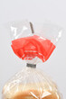 © nahhan - A close up shot of sliced white bread stored in a clear plastic bag with a red top and a grey clip over a plain white background