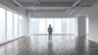 © CStock - A businessman stands alone in a spacious, empty office with large windows overlooking a city skyline.