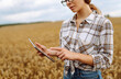© maxbelchenko - A female agronomist with a digital tablet works in a golden wheat field. A farmer checks the quality of the crop with a tablet in a field. Farming concept: a bountiful harvest.