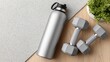 © MarinkaLev - fitness equipment still life, water bottle and dumbbells placed on the right side of a gym floor, clean texture background on the left side for text