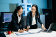 © Nuttapong punna - Two professional businesswomen analyzing reports and planning strategy at office desk. Teamwork, collaboration, management, consulting and modern corporate workplace.