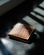 © Milos - A stylish brown crocodile wallet is showcased under soft lighting, accentuating its exquisite texture and craftsmanship, surrounded by contrasting shadows on a dark surface.