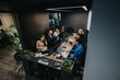 © qunica.com - A team of professionals works at a modern shared desk with multiple monitors and laptops. The scene shows collaboration in a spacious workplace with plants and festive decor.