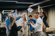 © qunica.com - A group of coworkers celebrates a project win, tossing papers and clapping. The energetic office scene shows teamwork and congratulations among friends.