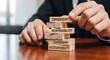 © Asghar - Businessman carefully balancing wooden blocks inscribed with core management concepts like ownership responsibility leadership and accountability