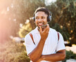 © Lumos sp - Young man enjoys sunny day while using smartphone and listening to music with earphones in urban setting, highlighting his joy and connection to the world around him