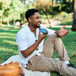 © Lumos sp - Young man enjoys sunny day while using smartphone in park, highlighting his joy and connection to the world around him