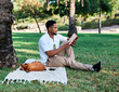© Lumos sp - Young man student businessman enjoys sunny day while reading a book in park, highlighting his joy and connection to the world around him