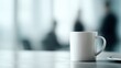 © Firadoaw - Calm professional office scene with sharp focus on a white coffee mug on desk, colleagues softly blurred in background