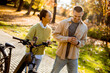 © BGStock72 - Couple sharing laughter while walking bicycles in a colorful autumn park