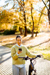 © BGStock72 - Korean woman enjoys a sunny autumn day while texting near her bike in a park