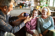 © Geber86 - Grandfather photographing granddaughter and grandmother with face masks at home