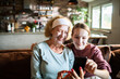 © Geber86 - Grandmother and teen granddaughter taking selfie with face masks at home