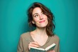 © Olena - Young female writer in profile, smiling as she writes in a notebook with a vivid color field behind