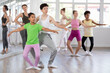 © JackF - Diligent African American preteen girl in bright green t-shirt and pink leggings training in pair with boy in ballet studio under guidance of female choreographer during group class
