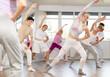 © JackF - Girl teen performs modern dances repeats movements of unrecognizable teacher together with friends during lesson at choreographic school. Hobbies, active pastime