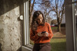 © Miljan Živković - Young woman engrossed in smart phone near window connecting outdoors