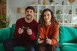 © Miljan Živković - Couple playing video games together on sofa at home