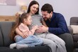 © New Africa - Pregnant woman, her husband and daughter on sofa at home