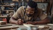 © VolumeThings - Black man in goggles and earmuffs measuring wood with pencil at workbench