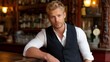 © liliyabatyrova - A young man with blonde hair presents a relaxed yet confident demeanor at a vintage bar. He wears a crisp white shirt under a dark vest. Soft lights create a warm atmosphere around him