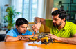 © StockImageFactory - Indian father helping kid repair toy using screw driver at home