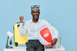 © SHOTPRIME STUDIO - Joyful man with dark skin wearing summer casual white shirt holding inflatable beach ball and travel accessories standing against light blue studio background future travel vacation concept