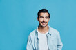© SHOTPRIME STUDIO - Smiling happy cheerful young man wear light blue shirt look at camera isolated on plain solid turquoise background studio portrait. People lifestyle concept