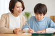 © milatas - 母に勉強を教えてもらう男の子
