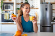 © Graphicroyalty - Happy woman in kitchen holding a glass of fresh orange juice and a half orange. Smiling female after workout enjoying healthy drink and vitamins. Concept of hydration, wellness, and citrus fruits.
