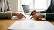 © 5 Grace Media - Two business people discussing documents and pointing at papers on a wooden table in an office setting.