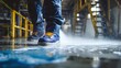 © Stock by Hemal - Worker in safety boots cleaning wet floor with water spray in industrial factory