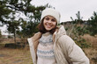 © SHOTPRIME STUDIO - Smiling woman wearing a beige puffer coat and patterned knit sweater outdoors in a chilly landscape with trees and open space.