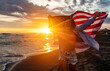 © NDABCREATIVITY - Happy woman smiling and running on beach with the US flag. July 4th independence day. Holiday