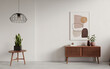 © BEGUMRUKEYA - Modern Minimalist Interior Scene with White Walls, Wooden Console Table, Abstract Art Print, and Green Potted Plants for Home Decor.