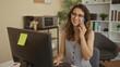 © Krakenimages.com - Woman typing on keyboard while smiling and holding smartphone to ear inside building at her desk; cheerful conversation.