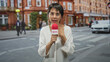 © Krakenimages.com - Woman holding red microphone labeled news, pointing thumb to chest while speaking into mic on street in front of brick building; concerned reporting.