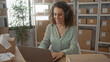 © Krakenimages.com - Woman typing on laptop amid delivery parcels in an office building, hands on keyboard and smiling while wearing headphones; small business productivity.