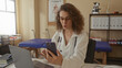 © Krakenimages.com - Woman doctor with stethoscope holds smartphone and gestures while seated in building clinic consulting via video; telehealth reassurance.